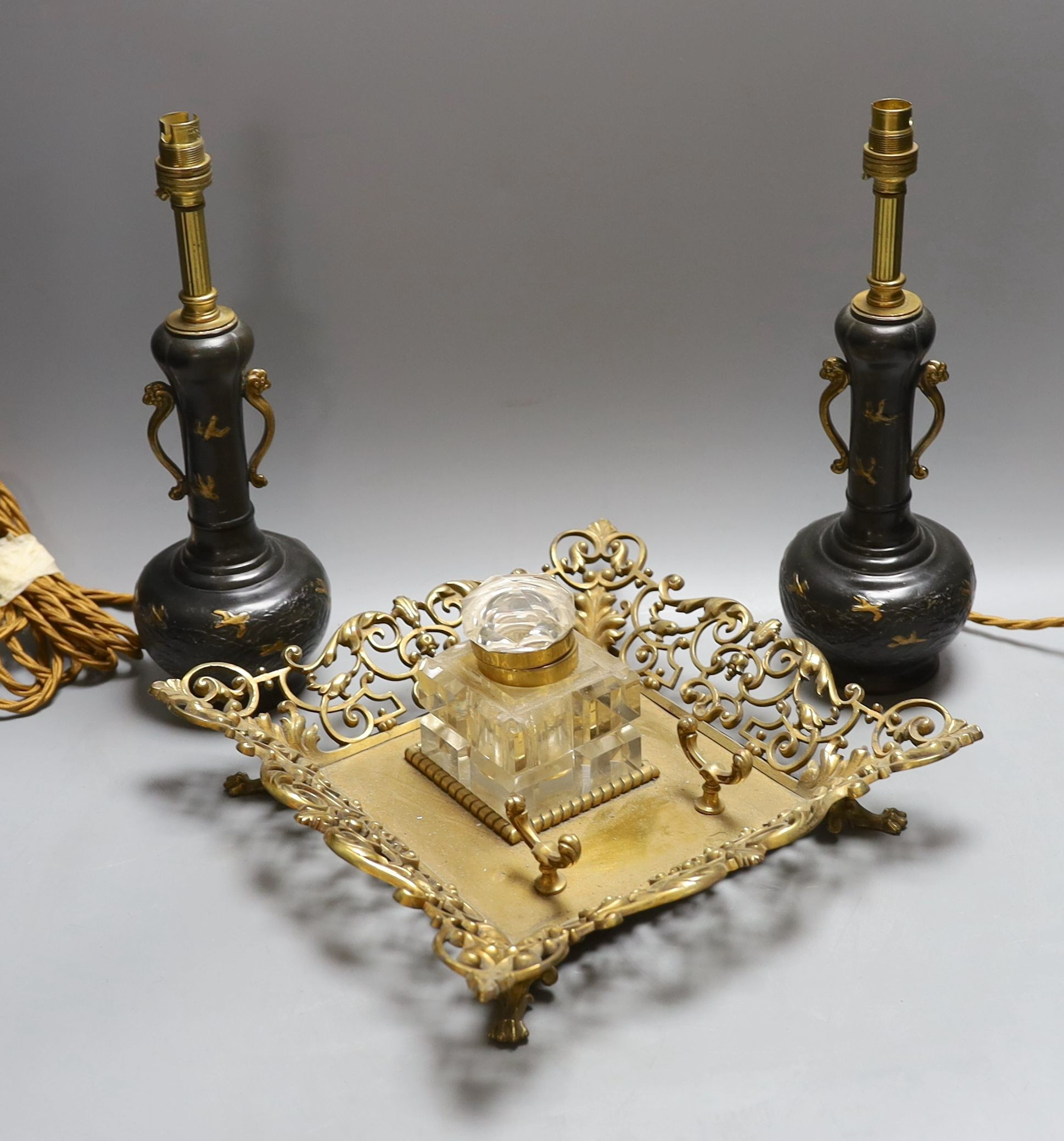 A decorative scroll brass inkstand, together with a pair of lamps, 29cm tall, (3)